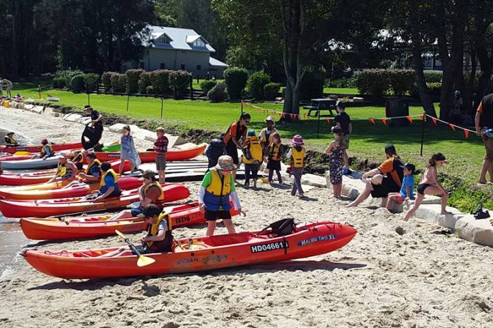 people pushing kayaks on sand
